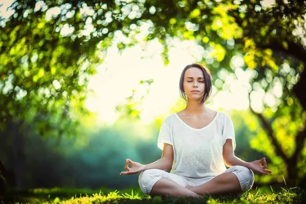 Image of a woman meditating in the park - Total Integrated Therapy